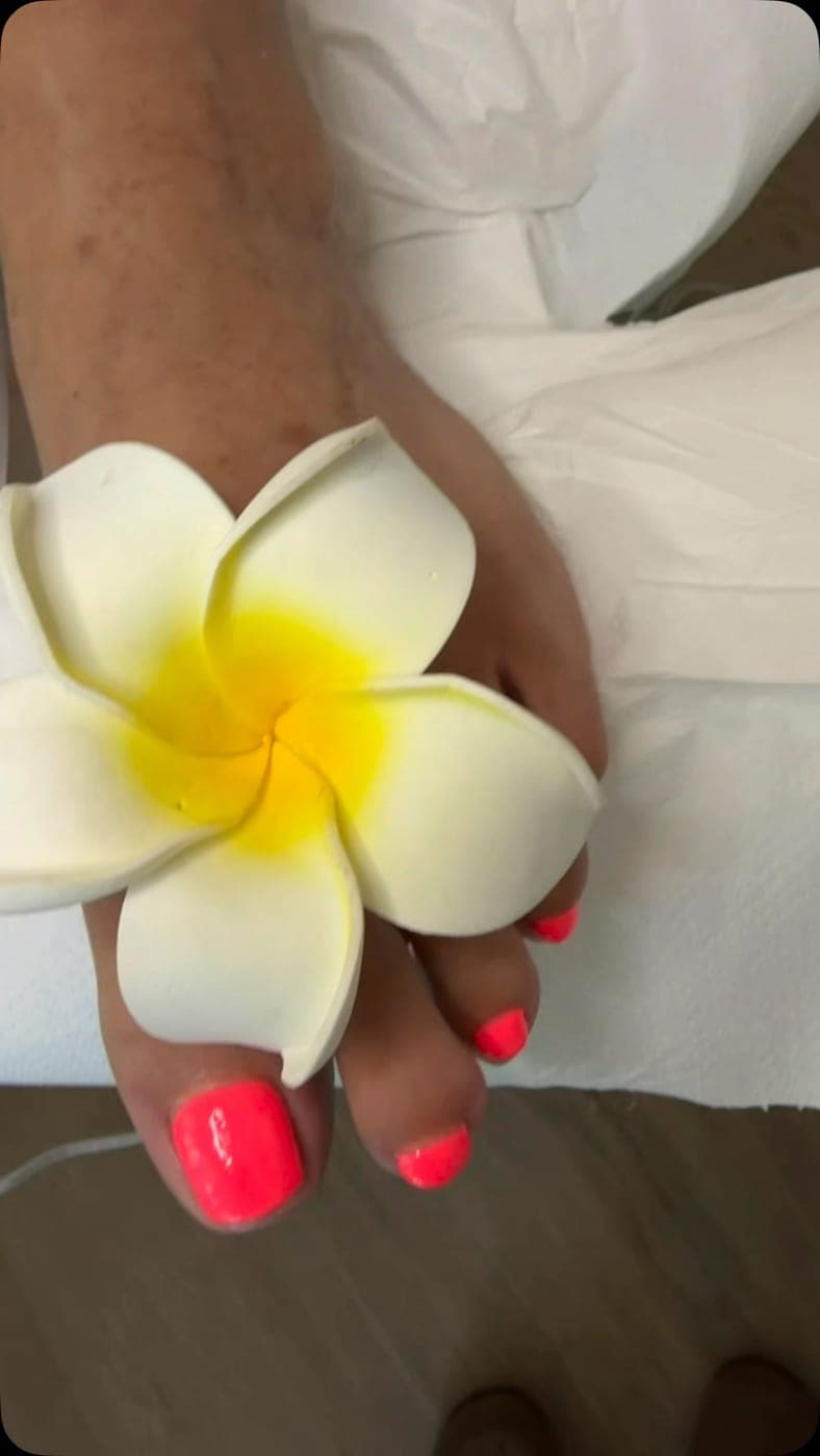 Korallrote Pediküre mit Plumeria-Blüte — Arbeit von Andrea